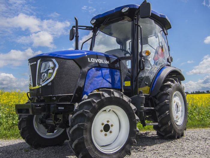 Blå Lovol 504 traktor parkerad på grusväg med gul åker i bakgrunden